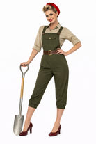 Woman in vintage-style green overalls holding a shovel on a white background